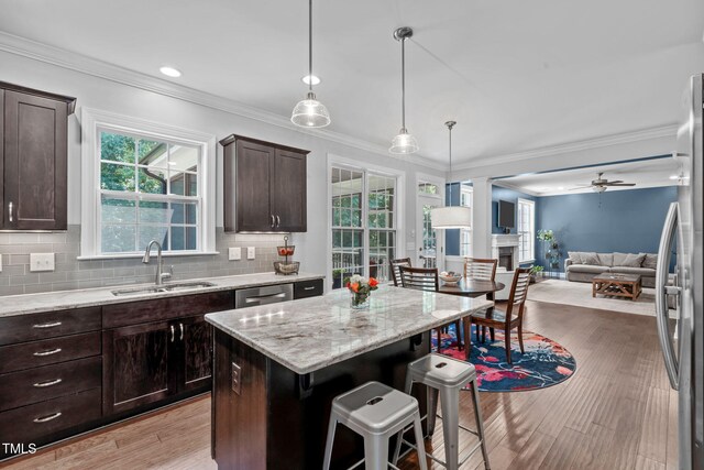 2716 Lake Waccamaw Trl, Apex, NC 27502 - kitchen featuring crown molding, dark brown cabinetry, a kitchen breakfast bar, open floor plan, and light stone counters