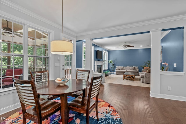 2716 Lake Waccamaw Trl, Apex, NC 27502 - dining area with ceiling fan, ornate columns, wood-type flooring, a fireplace, and crown molding