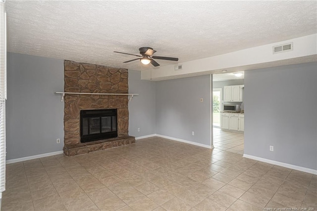 2408 Crabtree Ct, Fayetteville, NC 28304 - unfurnished living room with ceiling fan, a textured ceiling, a stone fireplace, and light tile patterned flooring