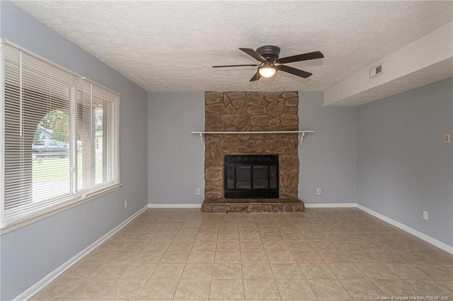 2408 Crabtree Ct, Fayetteville, NC 28304 - unfurnished living room with a ceiling fan, a textured ceiling, a stone fireplace, and light tile patterned floors