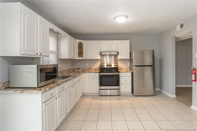 2408 Crabtree Ct, Fayetteville, NC 28304 - kitchen with appliances with stainless steel finishes, a textured ceiling, under cabinet range hood, light stone countertops, and white cabinetry