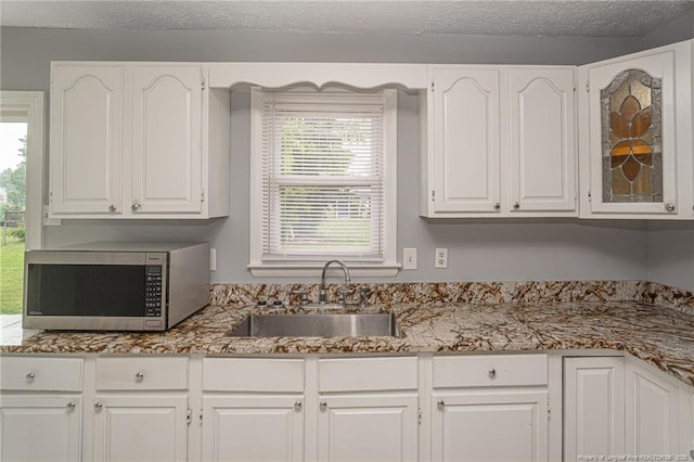 2408 Crabtree Ct, Fayetteville, NC 28304 - kitchen with stainless steel microwave, white cabinets, and light stone counters