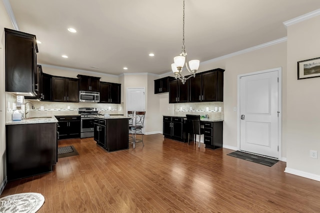 316 Vintage Holly Dr, Durham, NC 27703 - kitchen with appliances with stainless steel finishes, a chandelier, backsplash, a kitchen breakfast bar, and dark wood-style flooring