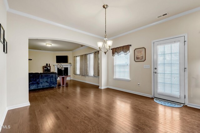 316 Vintage Holly Dr, Durham, NC 27703 - dining area with arched walkways, dark wood-style flooring, crown molding, a chandelier, and a fireplace