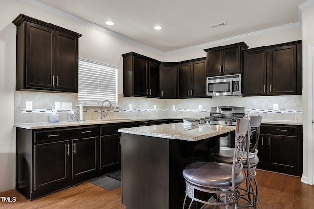 316 Vintage Holly Dr, Durham, NC 27703 - kitchen with stainless steel microwave, a kitchen breakfast bar, wood finished floors, a kitchen island, and recessed lighting