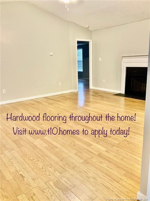 101 Horace Ct, Raeford, NC 28376 - unfurnished living room with wood finished floors, vaulted ceiling, a fireplace with flush hearth, and ceiling fan