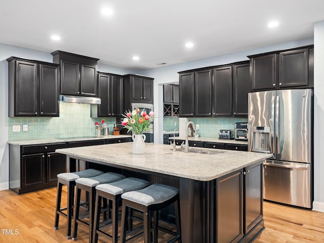 218 Inwood Forest Dr, Raleigh, NC 27603 - kitchen with stainless steel fridge, under cabinet range hood, dark cabinets, light wood-style flooring, and recessed lighting