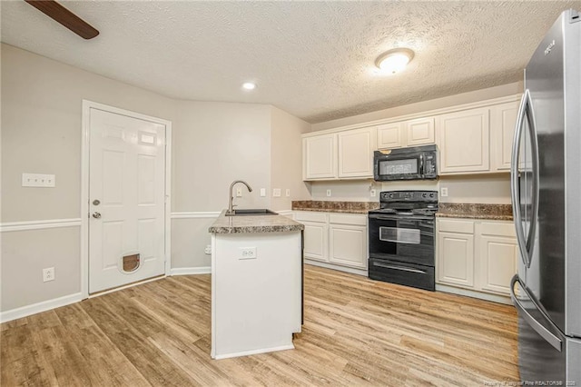 337 Buckeye Dr, Raeford, NC 28376 - kitchen with black appliances, light wood-style floors, white cabinets, a textured ceiling, and a kitchen island with sink