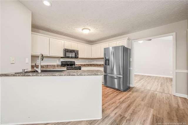 337 Buckeye Dr, Raeford, NC 28376 - kitchen featuring black appliances, a peninsula, light wood finished floors, white cabinets, and a textured ceiling