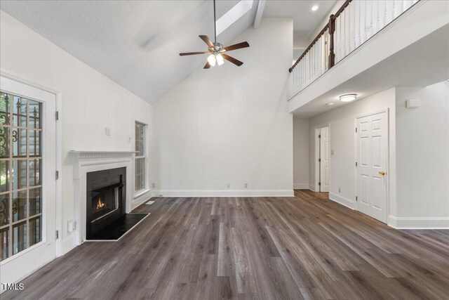 1209 Waterford Green Dr, Apex, NC 27502 - unfurnished living room with high vaulted ceiling, ceiling fan, a lit fireplace, and wood finished floors