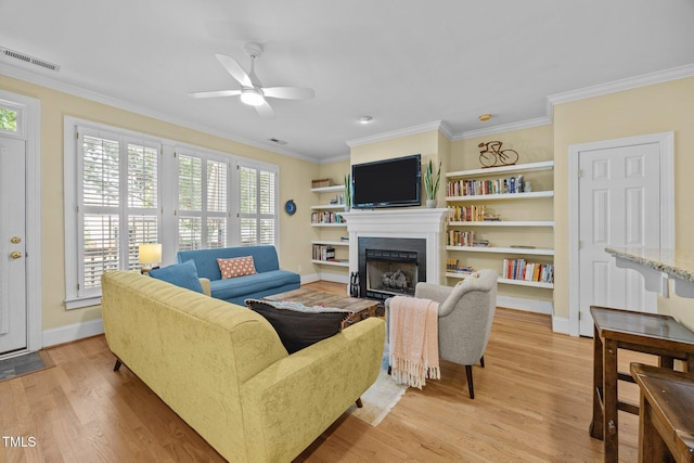 717 Mcclure Dr, Raleigh, NC 27603 - living room featuring ornamental molding, a fireplace with flush hearth, a ceiling fan, healthy amount of natural light, and light wood finished floors