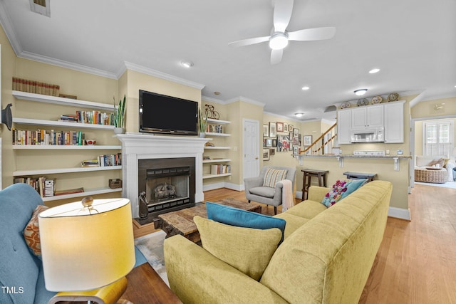 717 Mcclure Dr, Raleigh, NC 27603 - living room featuring stairway, a ceiling fan, light wood-type flooring, ornamental molding, and a fireplace with flush hearth