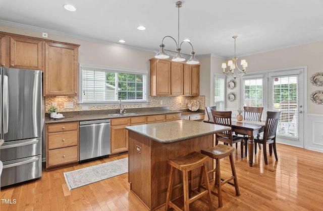 3806 Stoneybrook Dr, Durham, NC 27705 - kitchen featuring stainless steel appliances, light wood finished floors, healthy amount of natural light, a kitchen island, and crown molding