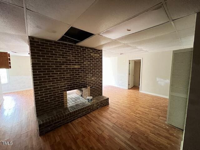 162 Black Horse Ln, Kittrell, NC 27544 - unfurnished living room featuring a paneled ceiling, wood finished floors, and a brick fireplace