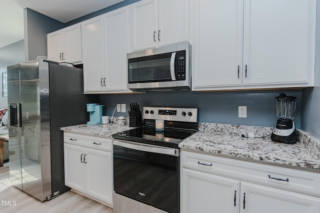 2586 Lacey Holt Rd, Graham, NC 27253 - kitchen with appliances with stainless steel finishes, light wood-type flooring, light stone counters, and white cabinetry