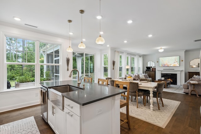 2013 Latham Oaks Ave, Wake Forest, NC 27587 - kitchen with dark countertops, dishwasher, crown molding, a glass covered fireplace, and dark wood-style flooring