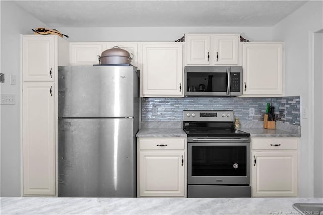 2140 Fargo Dr, Fayetteville, NC 28306 - kitchen with appliances with stainless steel finishes, white cabinetry, tasteful backsplash, and light stone counters