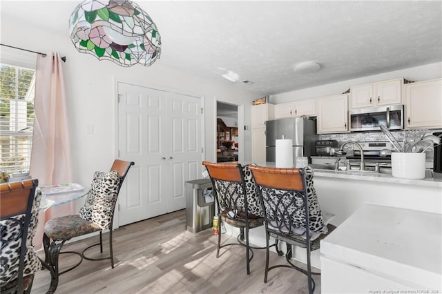 2140 Fargo Dr, Fayetteville, NC 28306 - kitchen with stainless steel appliances, light wood finished floors, light countertops, decorative backsplash, and a textured ceiling