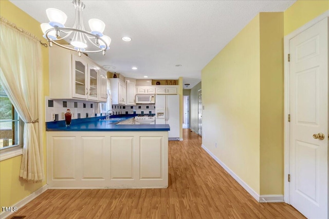 1379 Dr Martin Luther King Jr Blvd, Warrenton, NC 27589 - kitchen featuring white appliances, a chandelier, light wood-style floors, tasteful backsplash, and dark countertops