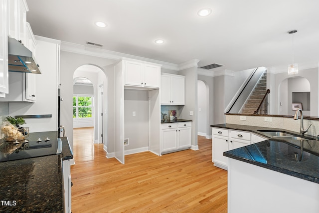 400 Swann Trl, Clayton, NC 27527 - kitchen featuring arched walkways, crown molding, under cabinet range hood, white cabinetry, and light wood-style floors