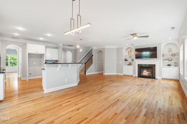 400 Swann Trl, Clayton, NC 27527 - kitchen with arched walkways, ceiling fan, white cabinetry, crown molding, and a kitchen bar