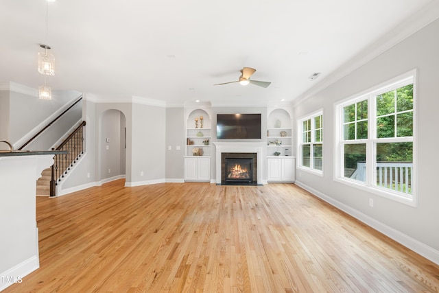 400 Swann Trl, Clayton, NC 27527 - unfurnished living room featuring light wood-style flooring, ceiling fan, crown molding, arched walkways, and a fireplace with flush hearth