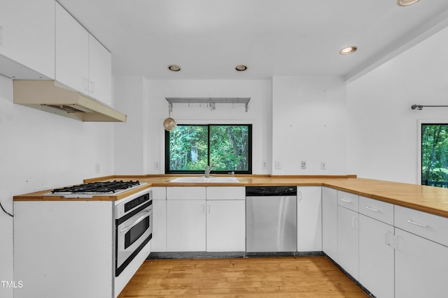 8510 Dunlee Falls Rd, Raleigh, NC 27613 - kitchen with dishwasher, oven, light wood finished floors, gas stovetop, and a peninsula