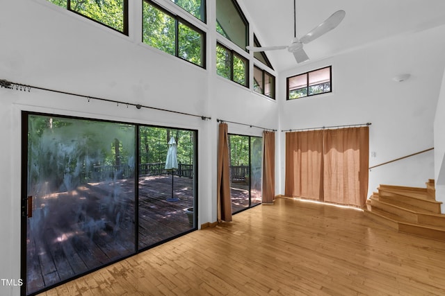8510 Dunlee Falls Rd, Raleigh, NC 27613 - unfurnished living room with a high ceiling, a ceiling fan, stairs, hardwood / wood-style flooring, and healthy amount of natural light
