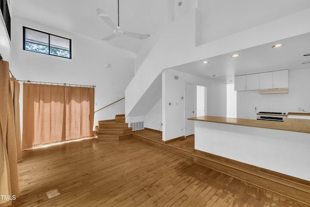 8510 Dunlee Falls Rd, Raleigh, NC 27613 - unfurnished living room with a towering ceiling, hardwood / wood-style floors, stairs, a ceiling fan, and recessed lighting