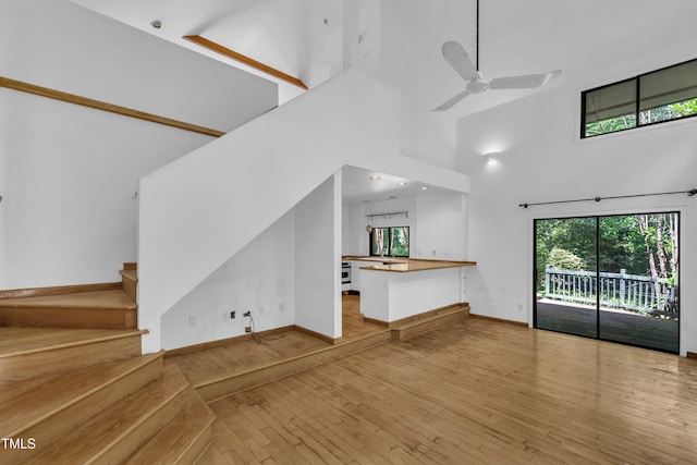 8510 Dunlee Falls Rd, Raleigh, NC 27613 - unfurnished living room featuring a high ceiling, hardwood / wood-style floors, ceiling fan, and stairs