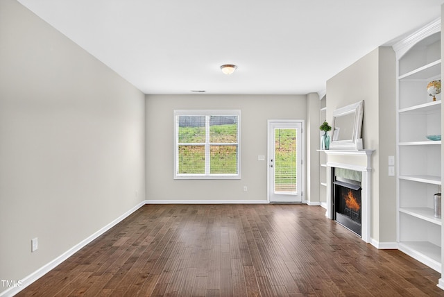 159 Forsyth Pkwy, Clayton, NC 27520 - unfurnished living room with dark wood-style floors, a warm lit fireplace, and built in shelves