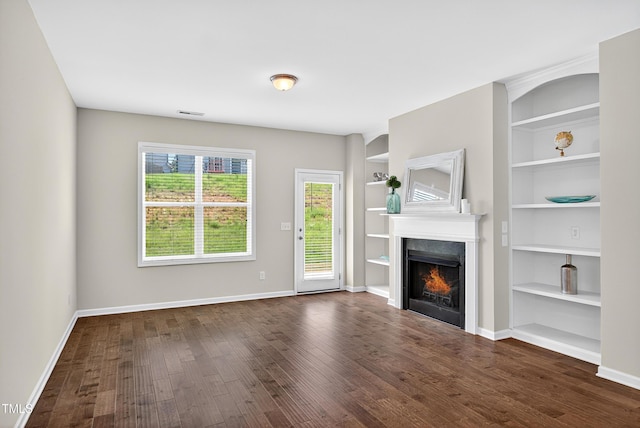 159 Forsyth Pkwy, Clayton, NC 27520 - unfurnished living room with a lit fireplace, dark wood-type flooring, and built in shelves