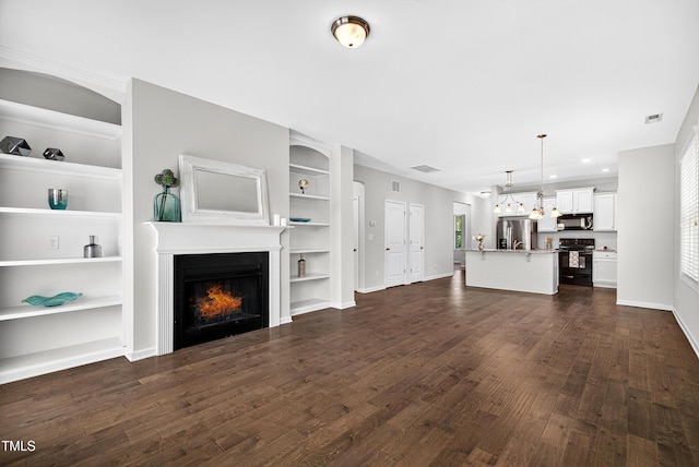 159 Forsyth Pkwy, Clayton, NC 27520 - unfurnished living room with a warm lit fireplace, dark wood-style flooring, and built in features