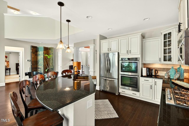 1806 Pattersons Mill Rd, Durham, NC 27703 - kitchen featuring stainless steel appliances, ornate columns, a breakfast bar, dark wood-type flooring, and pendant lighting