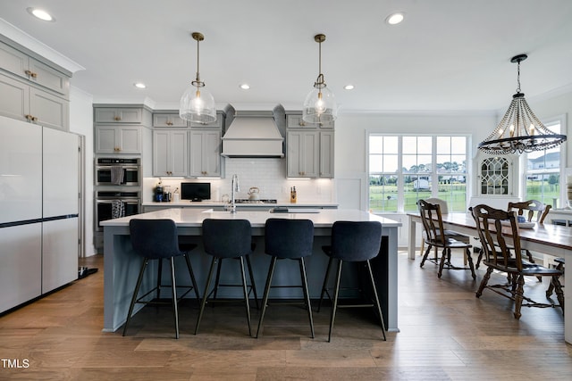 447 Marcellus Way, Clayton, NC 27527 - kitchen with gray cabinets, premium range hood, double oven, crown molding, and freestanding refrigerator