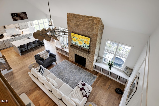 447 Marcellus Way, Clayton, NC 27527 - living area with high vaulted ceiling, a large fireplace, light wood-type flooring, and a chandelier