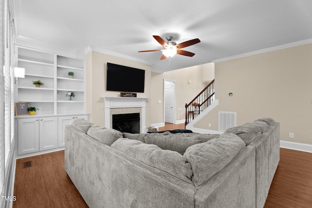 149 Hadley Ln, Clayton, NC 27527 - living area featuring dark wood-style floors, a ceiling fan, stairs, crown molding, and a fireplace
