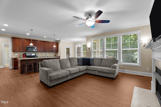 149 Hadley Ln, Clayton, NC 27527 - living area with a fireplace with flush hearth, a ceiling fan, wood finished floors, recessed lighting, and crown molding