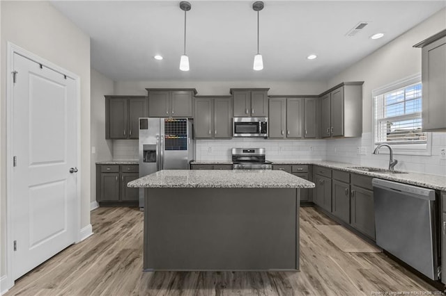 283 Leach Creek Dr, Raeford, NC 28376 - kitchen with appliances with stainless steel finishes, a center island, gray cabinetry, light stone countertops, and decorative backsplash