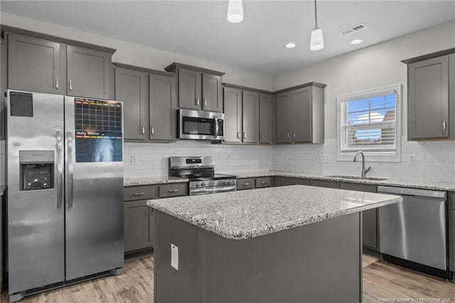 283 Leach Creek Dr, Raeford, NC 28376 - kitchen with appliances with stainless steel finishes, light stone countertops, light wood-style flooring, a kitchen island, and gray cabinetry