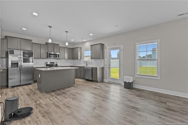 283 Leach Creek Dr, Raeford, NC 28376 - kitchen featuring appliances with stainless steel finishes, gray cabinets, a kitchen island, backsplash, and light wood-type flooring