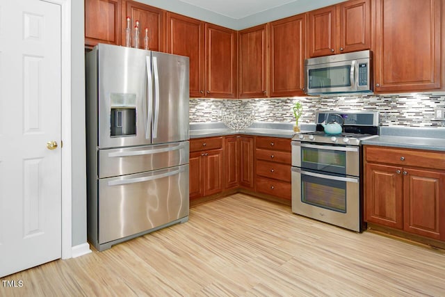 515 Wellingham Dr, Durham, NC 27713 - kitchen featuring stainless steel appliances, tasteful backsplash, light wood-style flooring, dark countertops, and brown cabinets