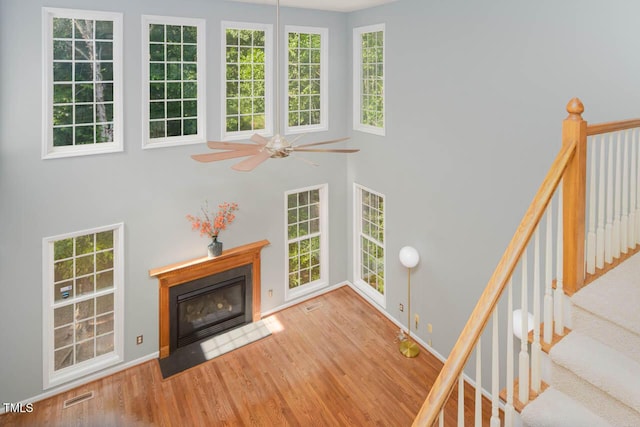 515 Wellingham Dr, Durham, NC 27713 - unfurnished living room featuring a ceiling fan, wood finished floors, a fireplace with flush hearth, and a towering ceiling