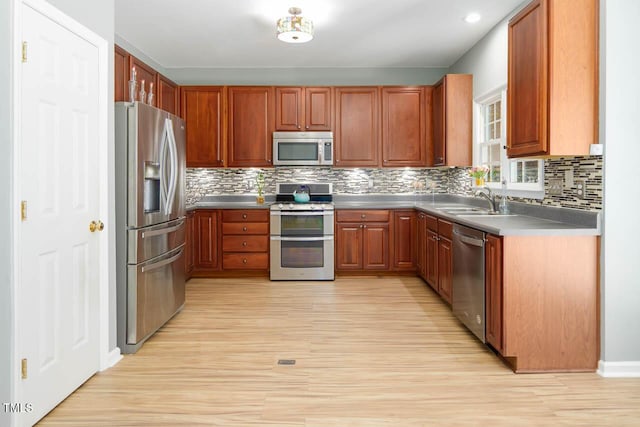 515 Wellingham Dr, Durham, NC 27713 - kitchen featuring stainless steel appliances, light wood-style flooring, tasteful backsplash, brown cabinets, and recessed lighting