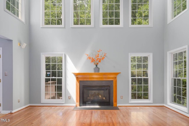 515 Wellingham Dr, Durham, NC 27713 - unfurnished living room with a high ceiling, wood finished floors, a fireplace with flush hearth, and plenty of natural light