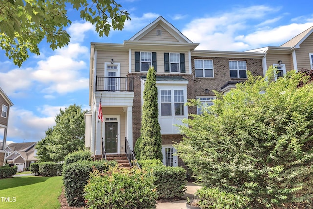 9216 Wooden Rd, Raleigh, NC 27617 - view of front of property with brick siding, a balcony, and a front lawn