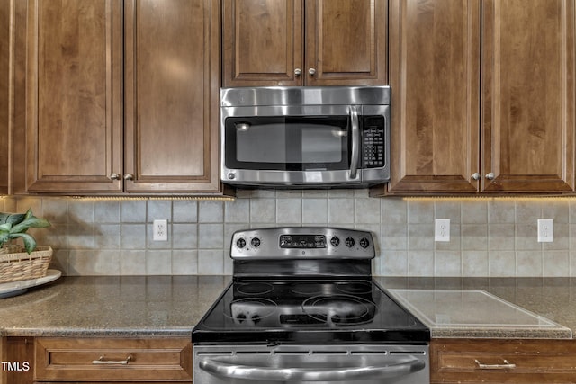 9216 Wooden Rd, Raleigh, NC 27617 - kitchen with appliances with stainless steel finishes, tasteful backsplash, dark stone counters, and brown cabinetry