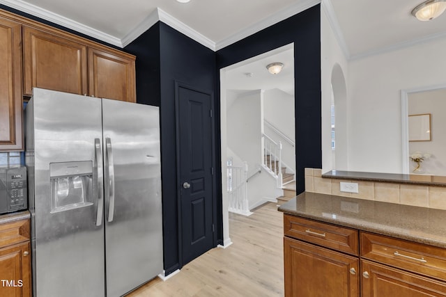 9216 Wooden Rd, Raleigh, NC 27617 - kitchen featuring appliances with stainless steel finishes, light wood-style floors, ornamental molding, arched walkways, and tasteful backsplash