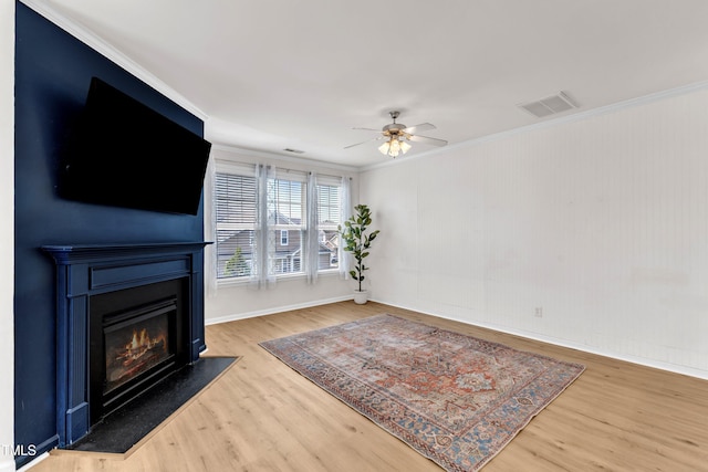 9216 Wooden Rd, Raleigh, NC 27617 - living room featuring a glass covered fireplace, wood finished floors, ceiling fan, and crown molding