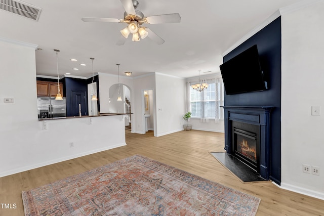 9216 Wooden Rd, Raleigh, NC 27617 - unfurnished living room featuring a fireplace, arched walkways, light wood-style flooring, a ceiling fan, and ornamental molding